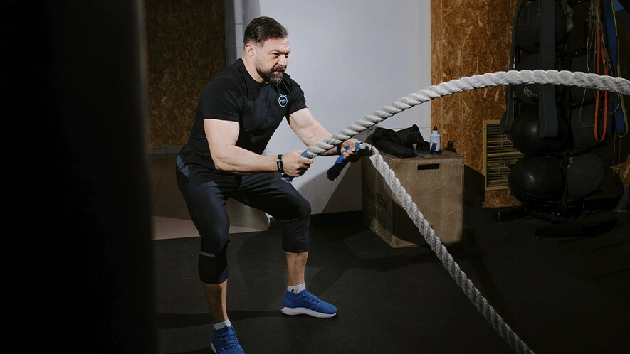 Мужчина выполняет упражнение с канатом в функциональной зоне